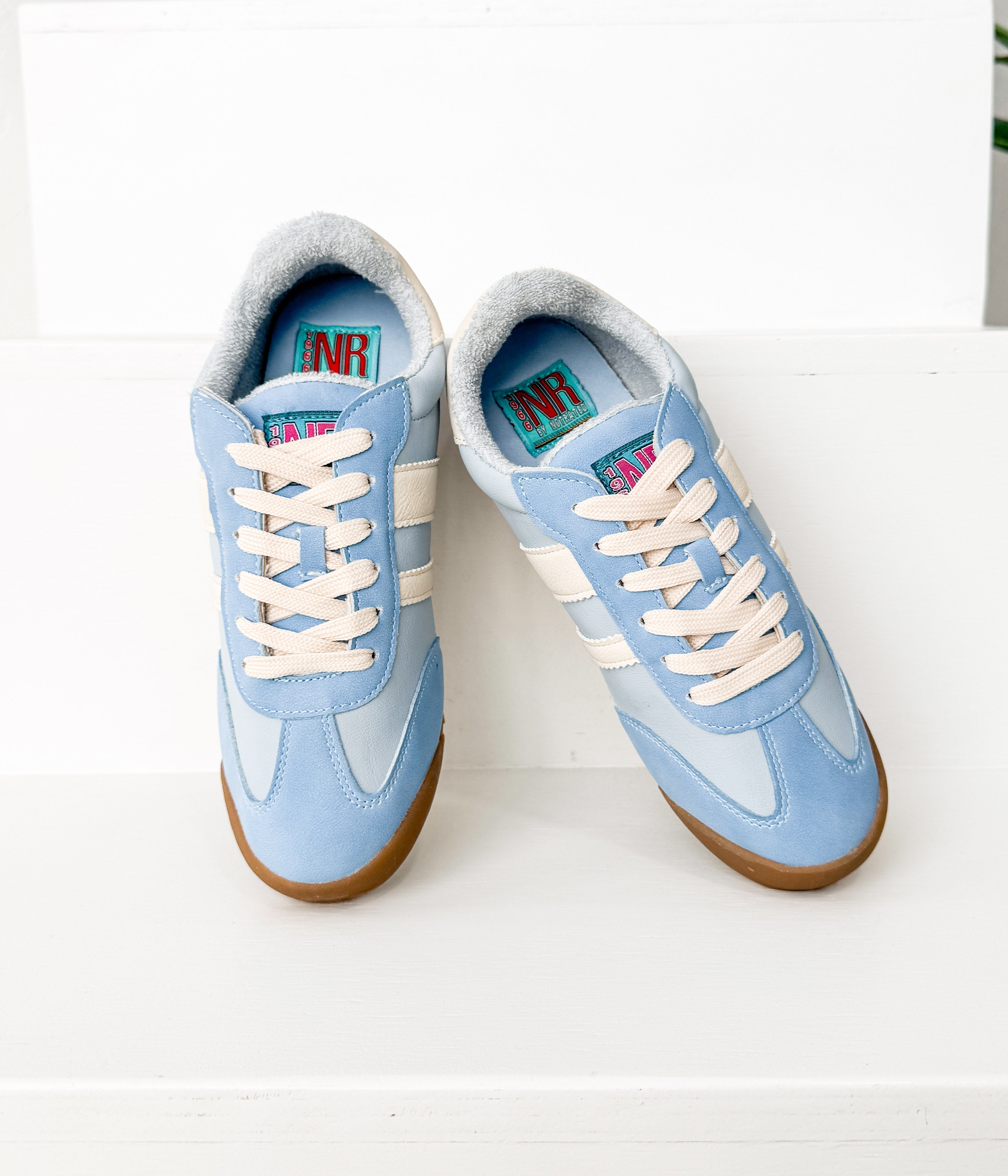 Pair of light blue sneakers with white laces on a white background