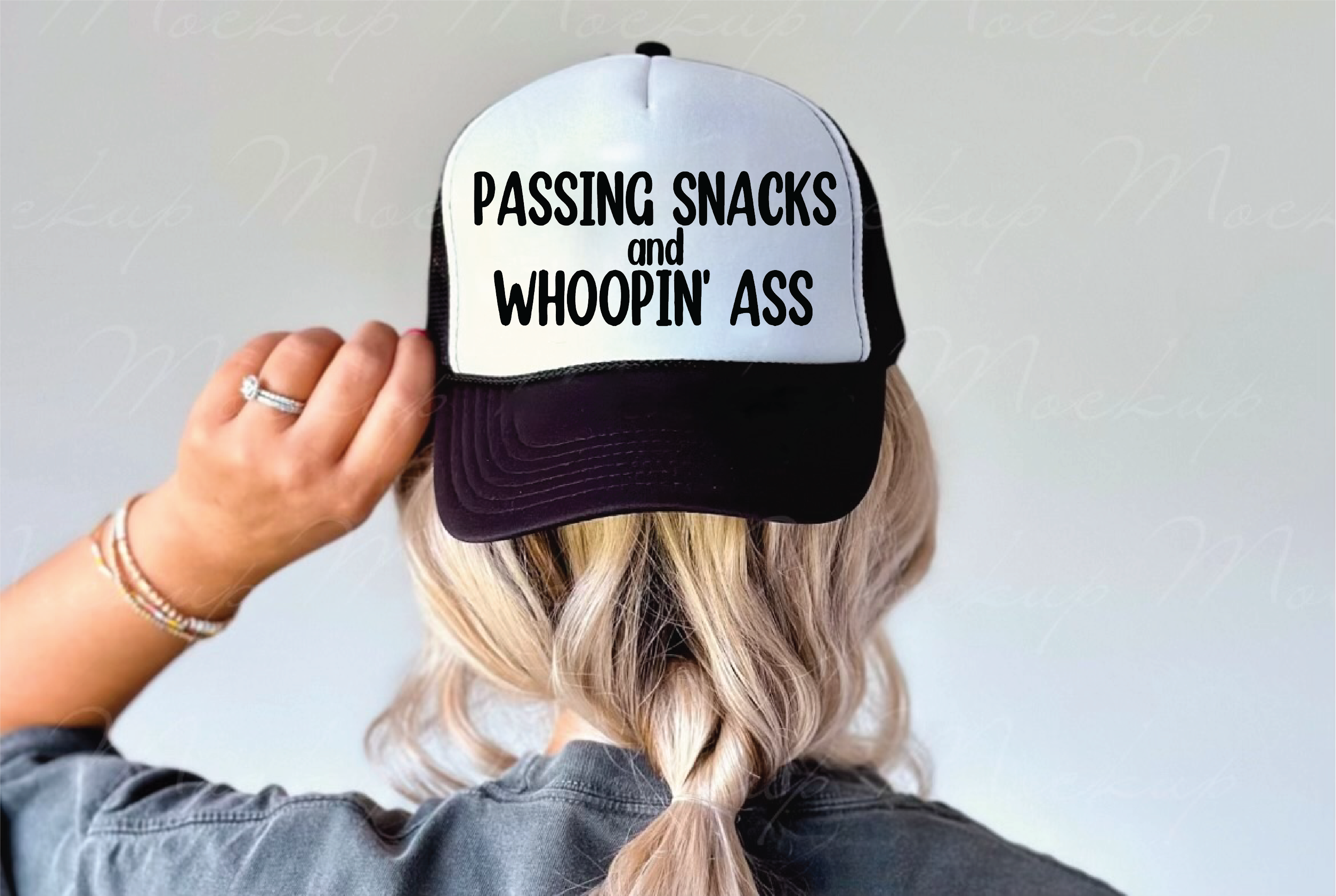 A person shown from behind wearing a black and white trucker hat with the text 'PASSING SNACKS and WHOOPIN' ASS' printed in black on the front panel.