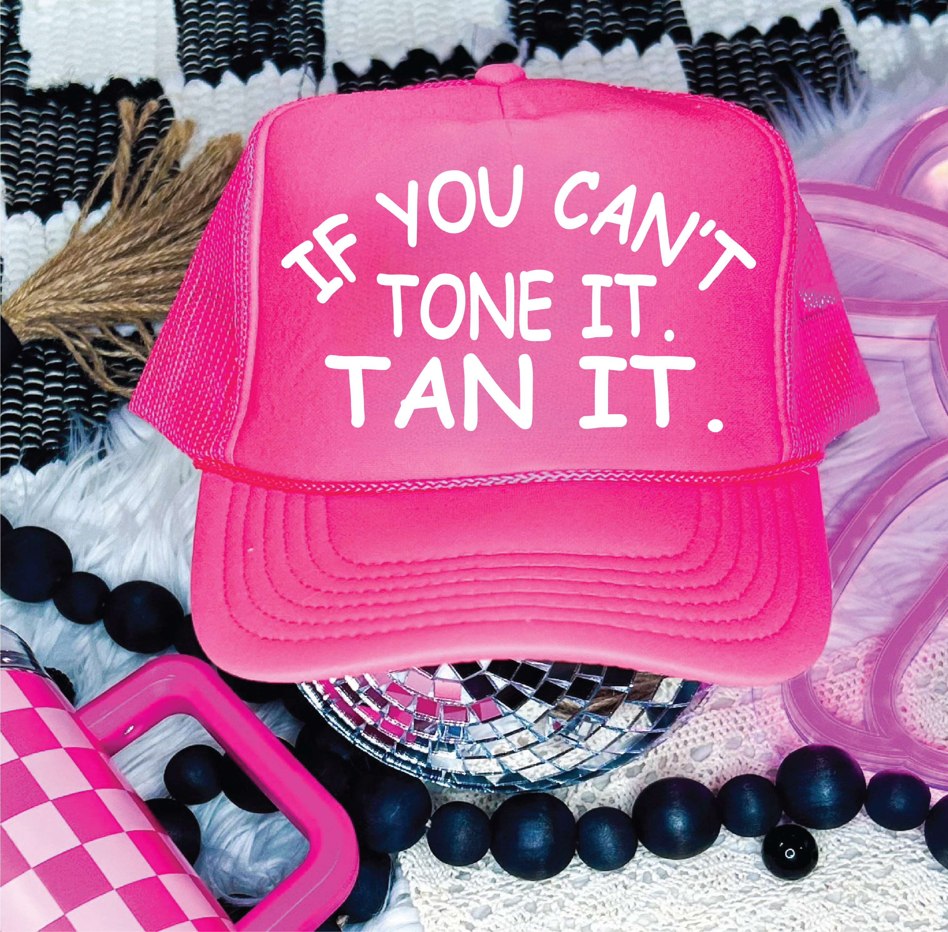 Pink cap with text 'If you can't tone it, tan it' on a patterned background