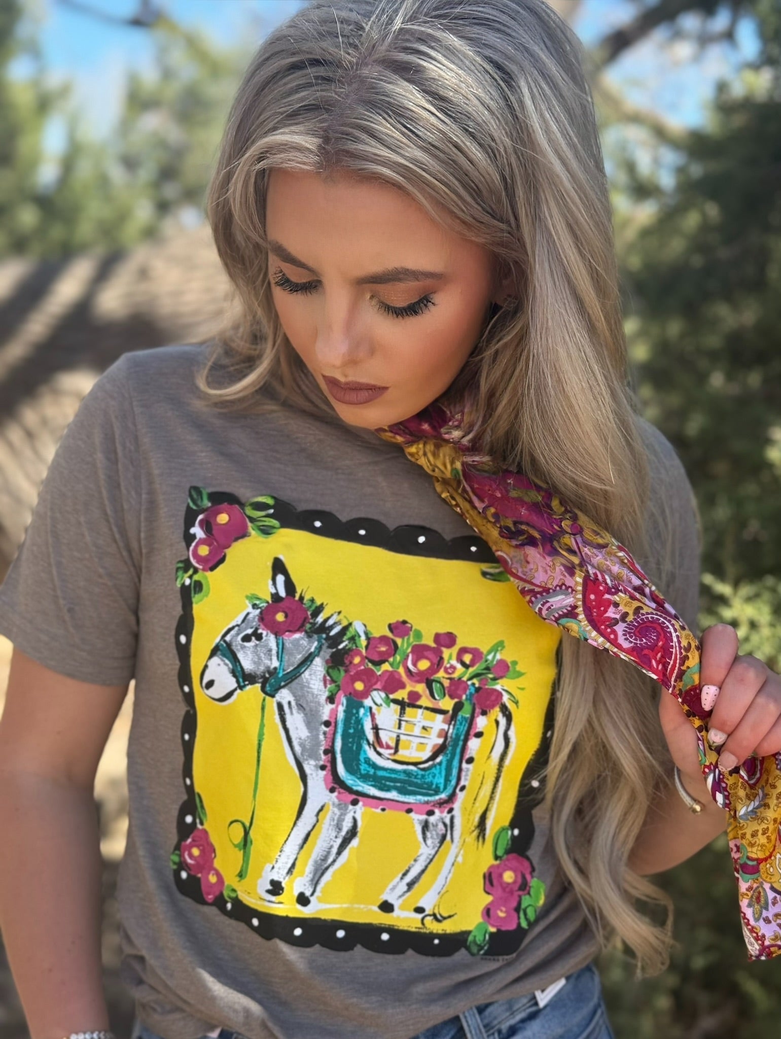 Woman wearing a gray t-shirt with a colorful donkey design outdoors