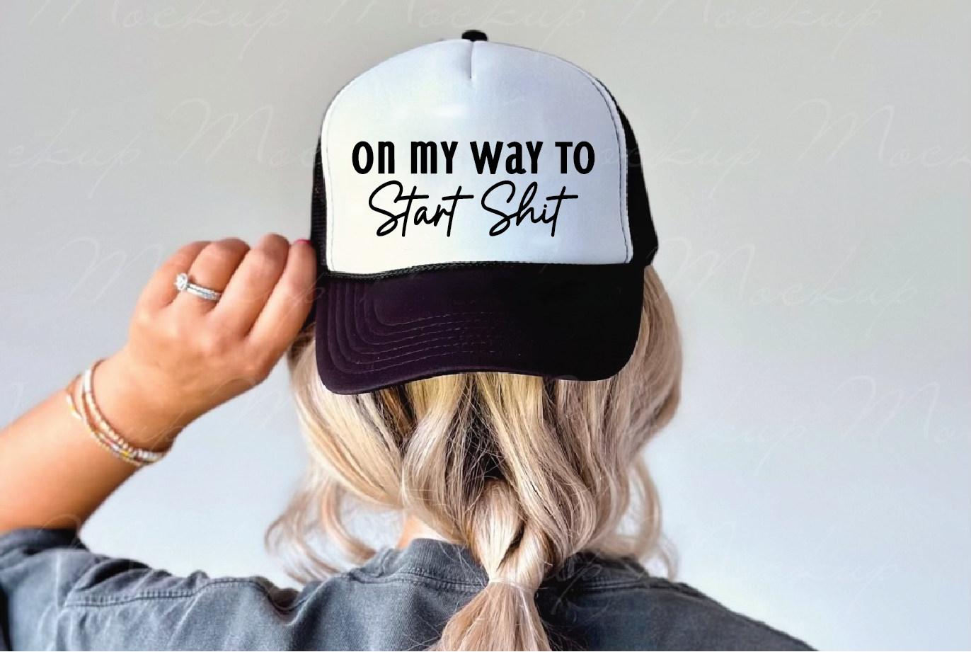 Person wearing a cap with 'On my way to start shit' text on a plain background
