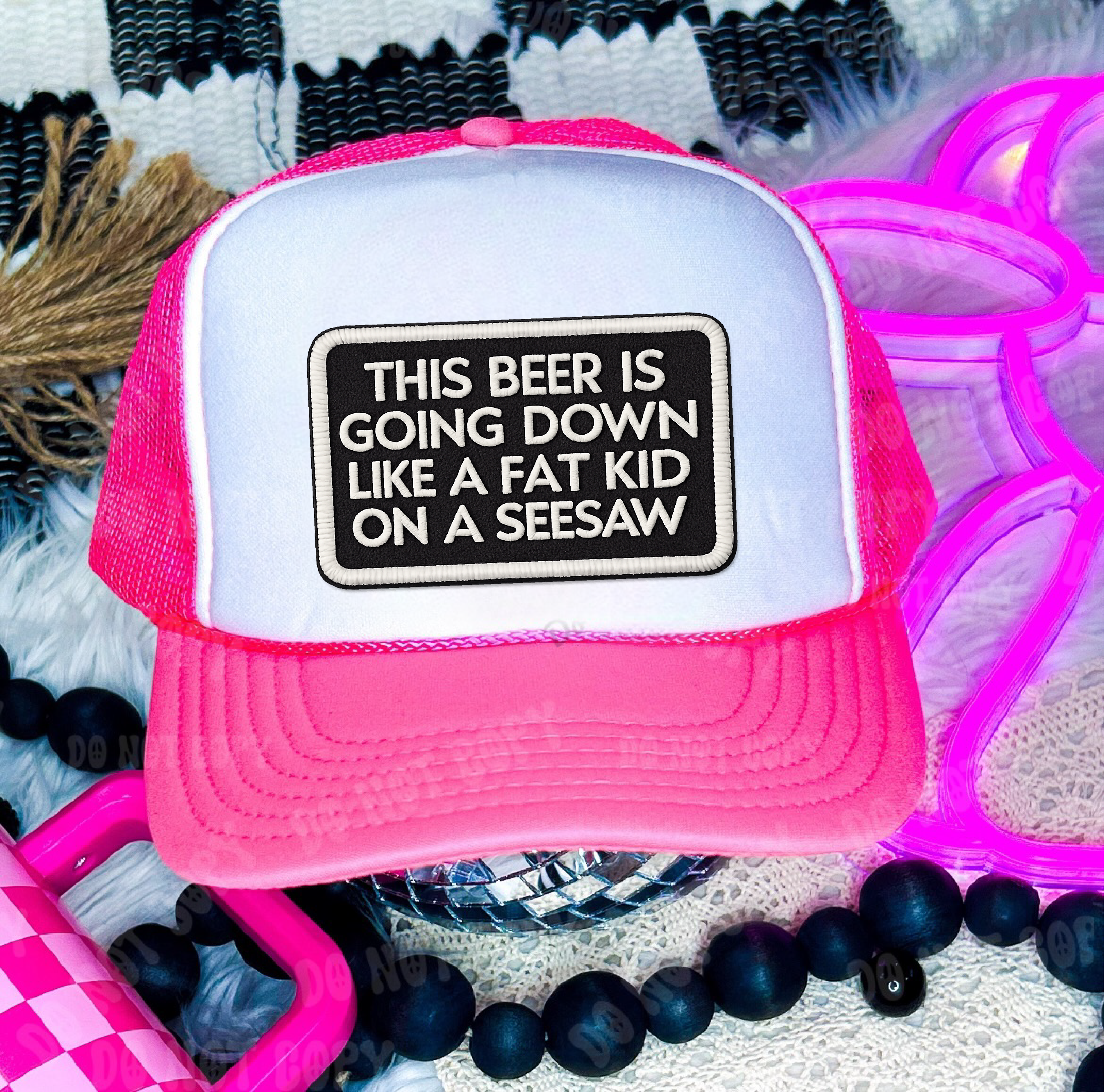 Pink and white trucker hat with humorous text design on a patterned background