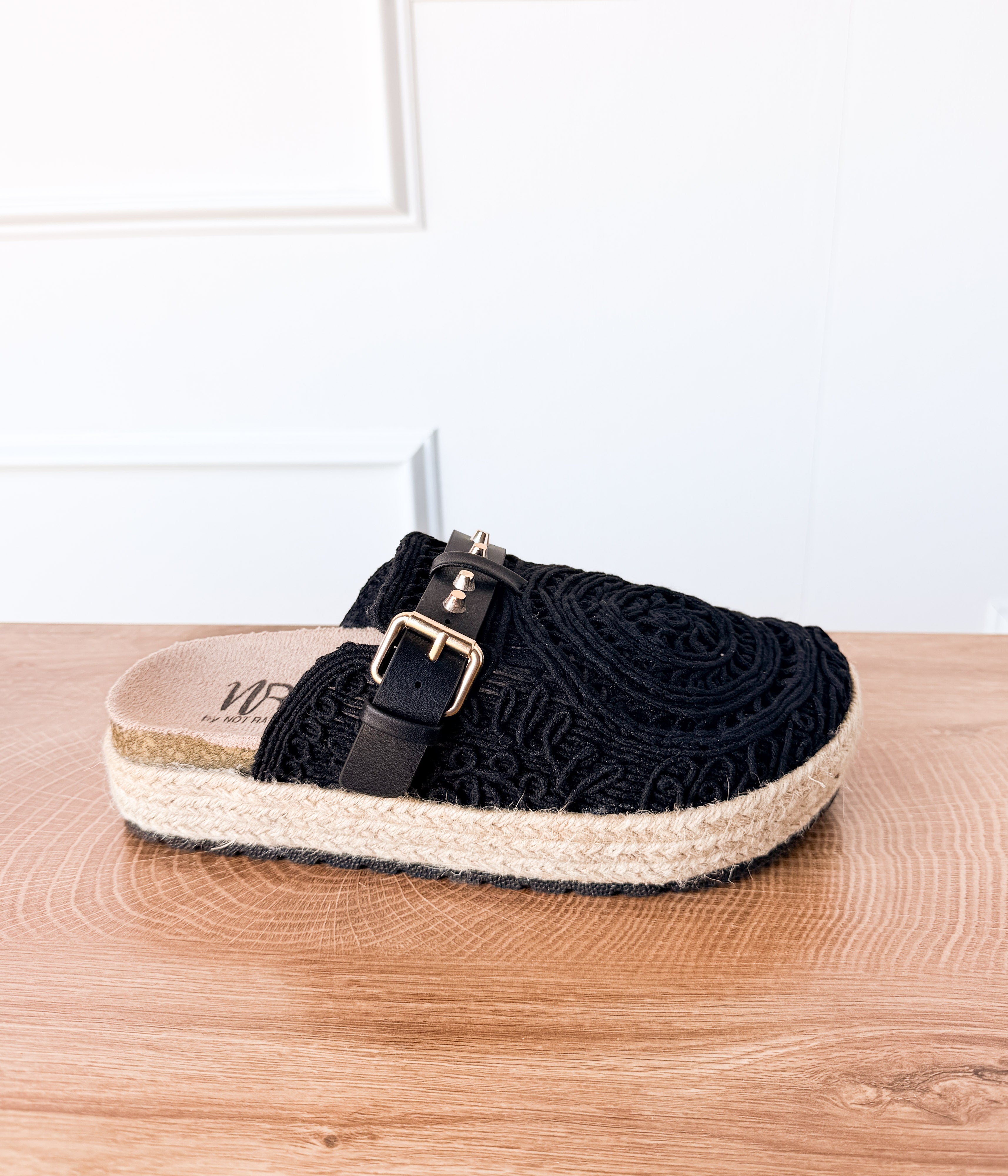 Black sandal with a strap on a wooden surface